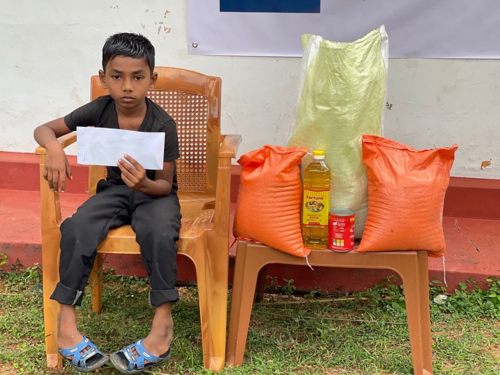 A child seated beside a food parcel provided through the orphans' care programme